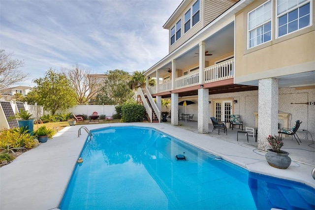 view of swimming pool with ceiling fan, a patio, and french doors