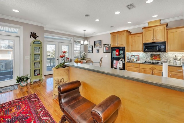 kitchen featuring black appliances, pendant lighting, light wood-type flooring, and ornamental molding