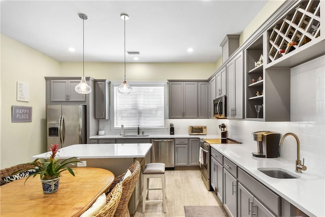 kitchen featuring sink, light hardwood / wood-style flooring, hanging light fixtures, and appliances with stainless steel finishes