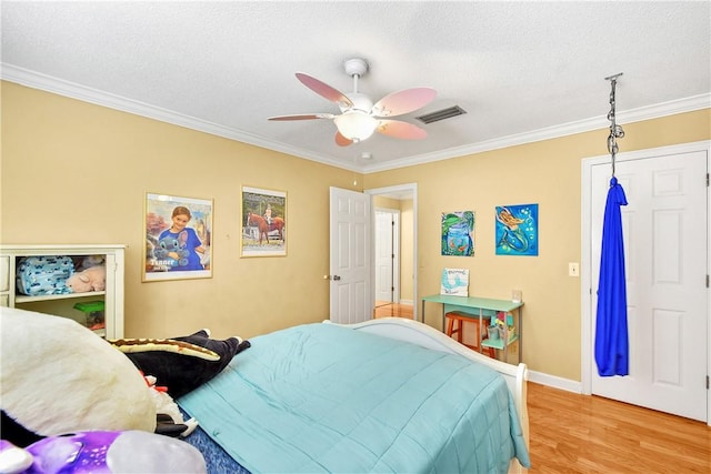 bedroom with ceiling fan, light wood-type flooring, a textured ceiling, a closet, and ornamental molding