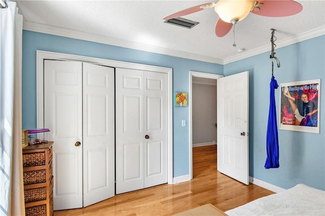 bedroom with ceiling fan, crown molding, wood-type flooring, and a textured ceiling