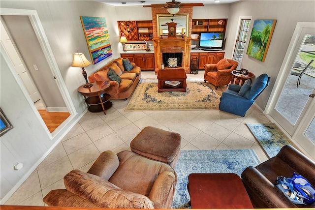 tiled living room with ceiling fan and a brick fireplace