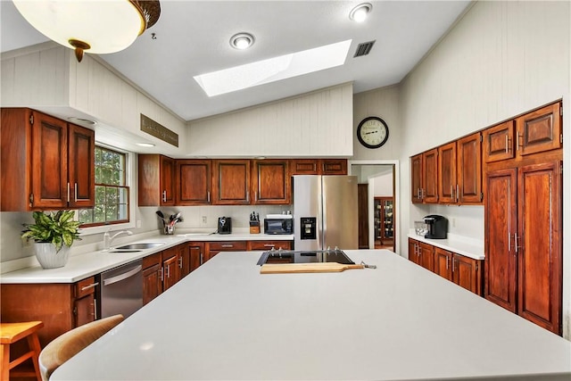 kitchen with appliances with stainless steel finishes, lofted ceiling with skylight, a breakfast bar area, and sink