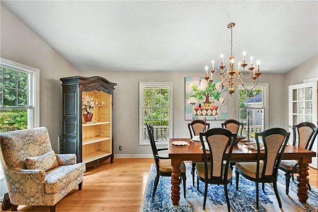 dining space featuring plenty of natural light, light hardwood / wood-style floors, a textured ceiling, and an inviting chandelier