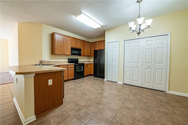 kitchen with pendant lighting, black appliances, sink, a notable chandelier, and kitchen peninsula