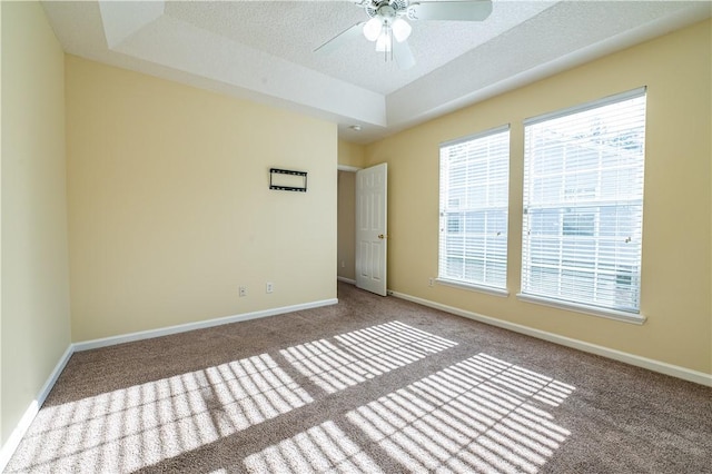 spare room with ceiling fan, a tray ceiling, carpet floors, and a textured ceiling