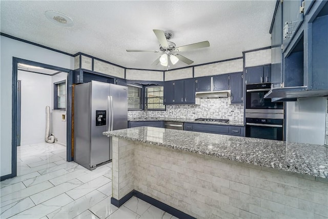 1501 Charles St, Waycross, GA 31501 - kitchen with appliances with stainless steel finishes, under cabinet range hood, ceiling fan, stone counters, and a textured ceiling