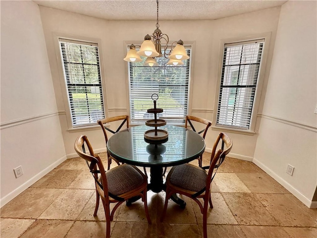 dining room featuring a textured ceiling, a chandelier, baseboards, and stone tile floors