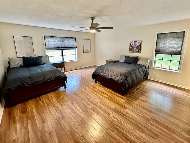 bedroom with baseboards, light wood-type flooring, and multiple windows