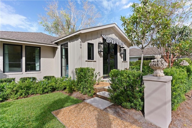 bungalow-style house featuring board and batten siding, brick siding, and a shingled roof