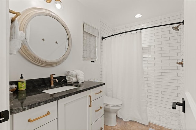 full bathroom featuring a tile shower, vanity, and toilet