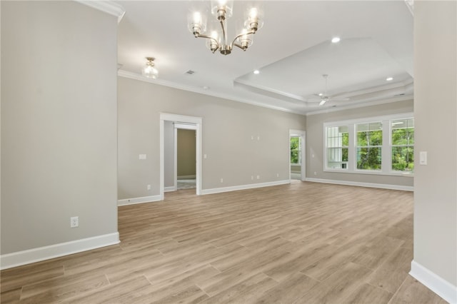 180 Ossabaw Way, Waverly, GA 31565 - unfurnished living room featuring crown molding, a raised ceiling, light wood-style flooring, a chandelier, and a ceiling fan