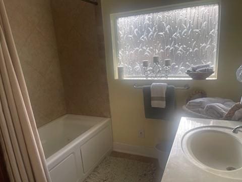 bathroom with a tub, sink, and plenty of natural light