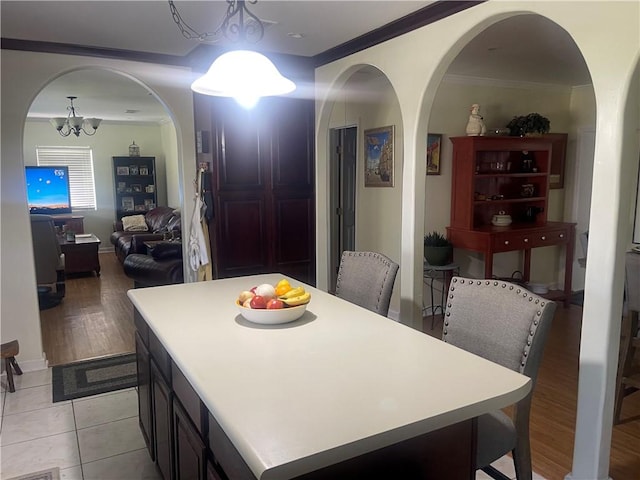 tiled dining space with crown molding and a chandelier