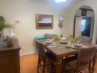 dining space with ornamental molding and light wood-type flooring