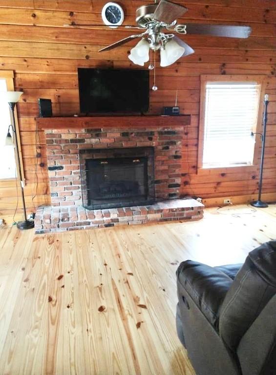 1518 To Jones Rd, Reidsville, GA 30453 - living room with wooden walls, wood finished floors, ceiling fan, and a brick fireplace