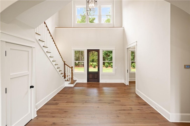 1241 Pikes Bluff Rd, Saint Simons Island, GA 31522 - foyer featuring a chandelier, wood finished floors, healthy amount of natural light, a high ceiling, and stairs