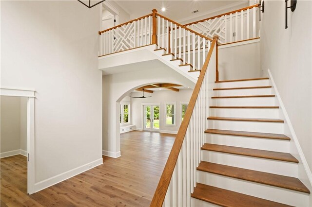 1241 Pikes Bluff Rd, Saint Simons Island, GA 31522 - stairway featuring wood finished floors, arched walkways, a towering ceiling, a ceiling fan, and recessed lighting