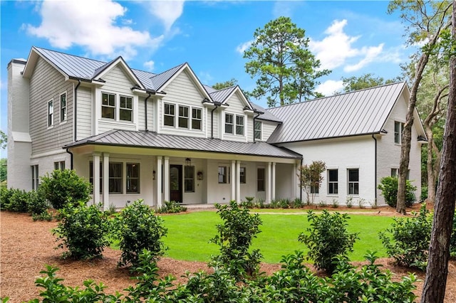 view of front facade with a standing seam roof, metal roof, and a front lawn