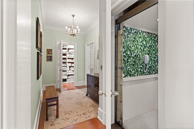 entryway with hardwood / wood-style flooring, crown molding, and an inviting chandelier