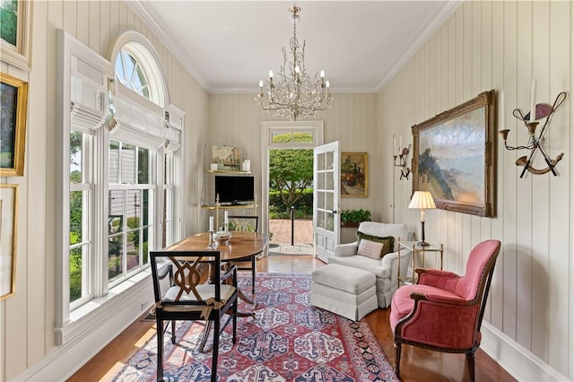 sitting room featuring french doors, wood walls, a chandelier, hardwood / wood-style flooring, and ornamental molding