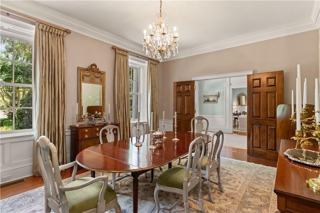 dining room with plenty of natural light, an inviting chandelier, ornamental molding, and light hardwood / wood-style flooring