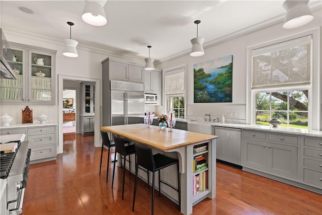 kitchen featuring gray cabinetry, a kitchen breakfast bar, built in appliances, hardwood / wood-style flooring, and a kitchen island