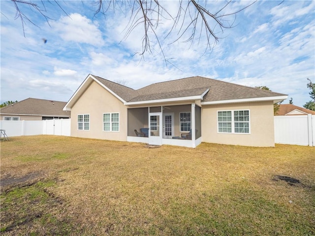 rear view of house with a sunroom and a lawn