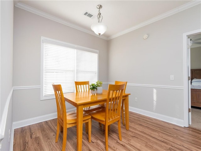 dining area featuring crown molding and light wood-type flooring