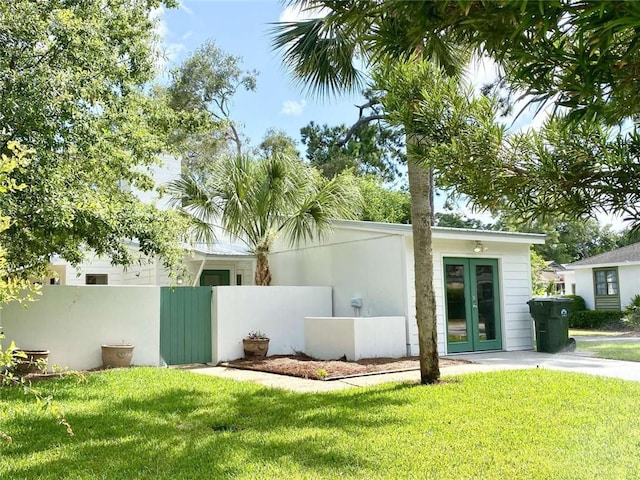 view of side of property with french doors and a lawn