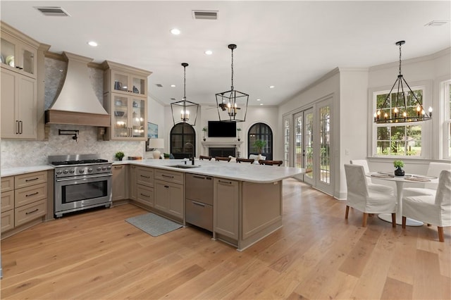 kitchen featuring a peninsula, premium range hood, a sink, visible vents, and high end stainless steel range oven