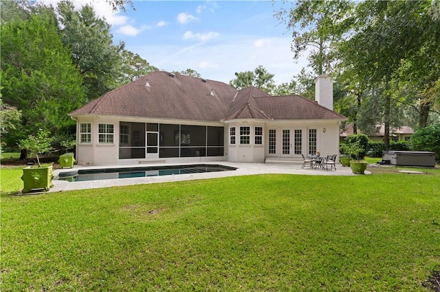 rear view of house with a chimney, a lawn, a patio area, and a sunroom