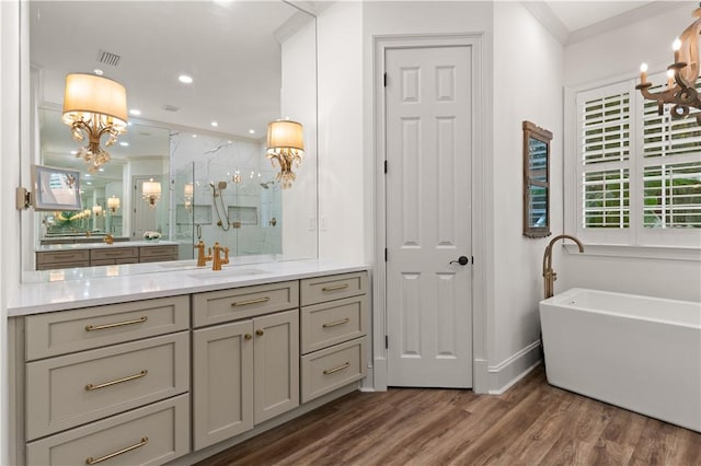 bathroom featuring a stall shower, a soaking tub, wood finished floors, an inviting chandelier, and vanity