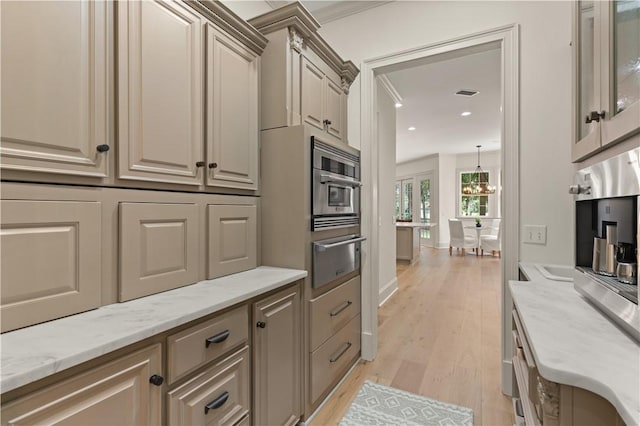 kitchen featuring cream cabinets, light wood-style flooring, visible vents, light stone countertops, and a warming drawer