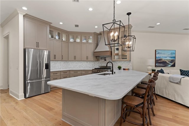 kitchen with custom range hood, a sink, light wood-style flooring, and stainless steel fridge with ice dispenser