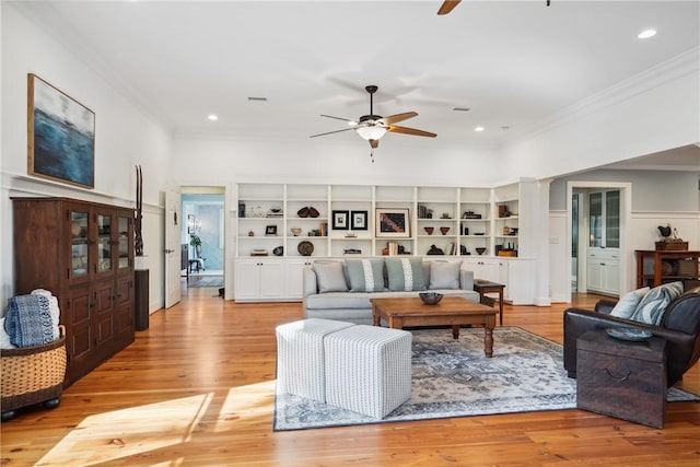 living room featuring built in shelves, ornamental molding, light hardwood / wood-style floors, and ceiling fan