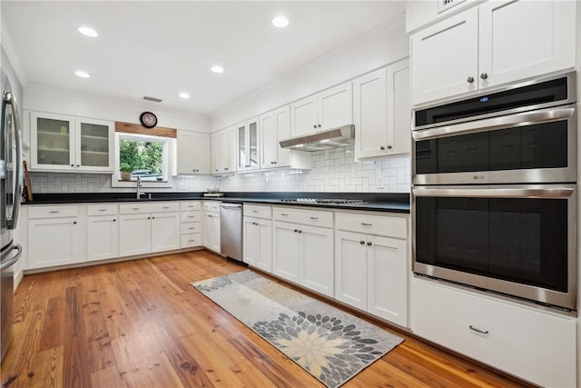 kitchen featuring appliances with stainless steel finishes, sink, white cabinets, and light wood-type flooring