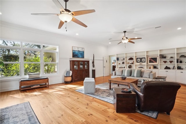 living room with crown molding, ceiling fan, and light wood-type flooring