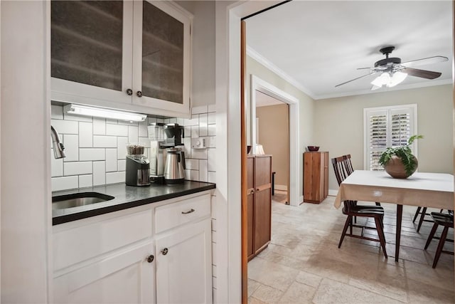 kitchen with sink, ornamental molding, white cabinets, ceiling fan, and backsplash