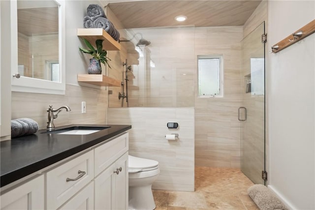 bathroom featuring vanity, toilet, an enclosed shower, and tile walls