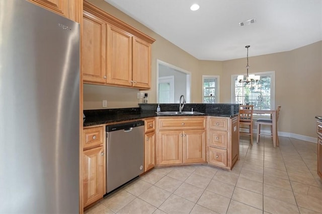 kitchen featuring dark stone counters, an inviting chandelier, sink, light tile patterned floors, and stainless steel appliances