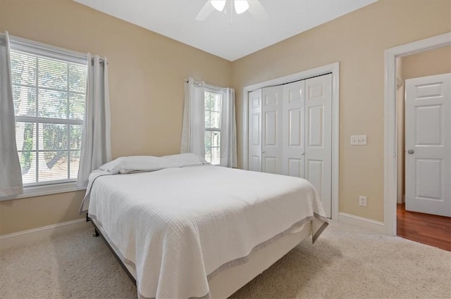 carpeted bedroom with ceiling fan, a closet, and multiple windows