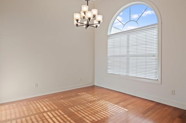 spare room featuring light wood-type flooring and an inviting chandelier