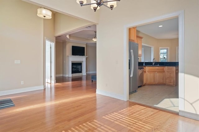 interior space with ceiling fan with notable chandelier, stainless steel appliances, light hardwood / wood-style flooring, and sink