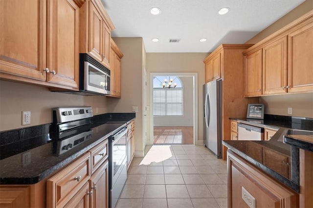 kitchen with dark stone countertops, light tile patterned flooring, a chandelier, and appliances with stainless steel finishes