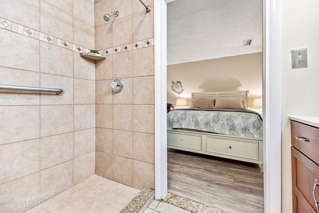 bathroom with a tile shower, wood-type flooring, and a textured ceiling