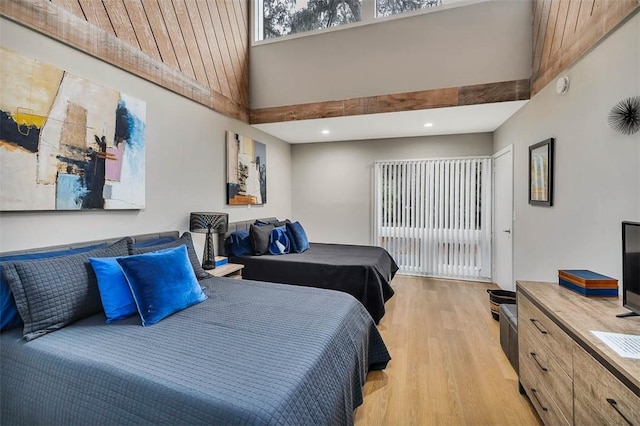 bedroom featuring a high ceiling and light wood-type flooring