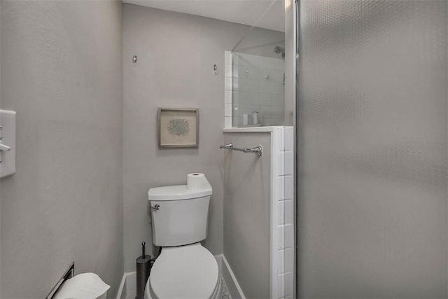 bathroom featuring a shower with shower door and toilet