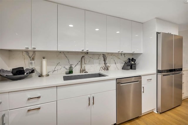 kitchen featuring white cabinetry, sink, light hardwood / wood-style floors, and appliances with stainless steel finishes