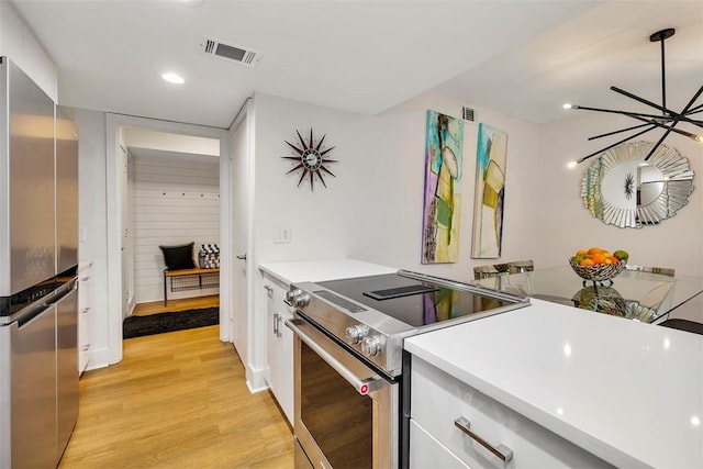 kitchen with stainless steel appliances, light hardwood / wood-style flooring, hanging light fixtures, and white cabinets